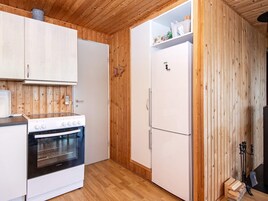 Una cocina compacta con paredes de madera, estufa blanca y refrigerador.