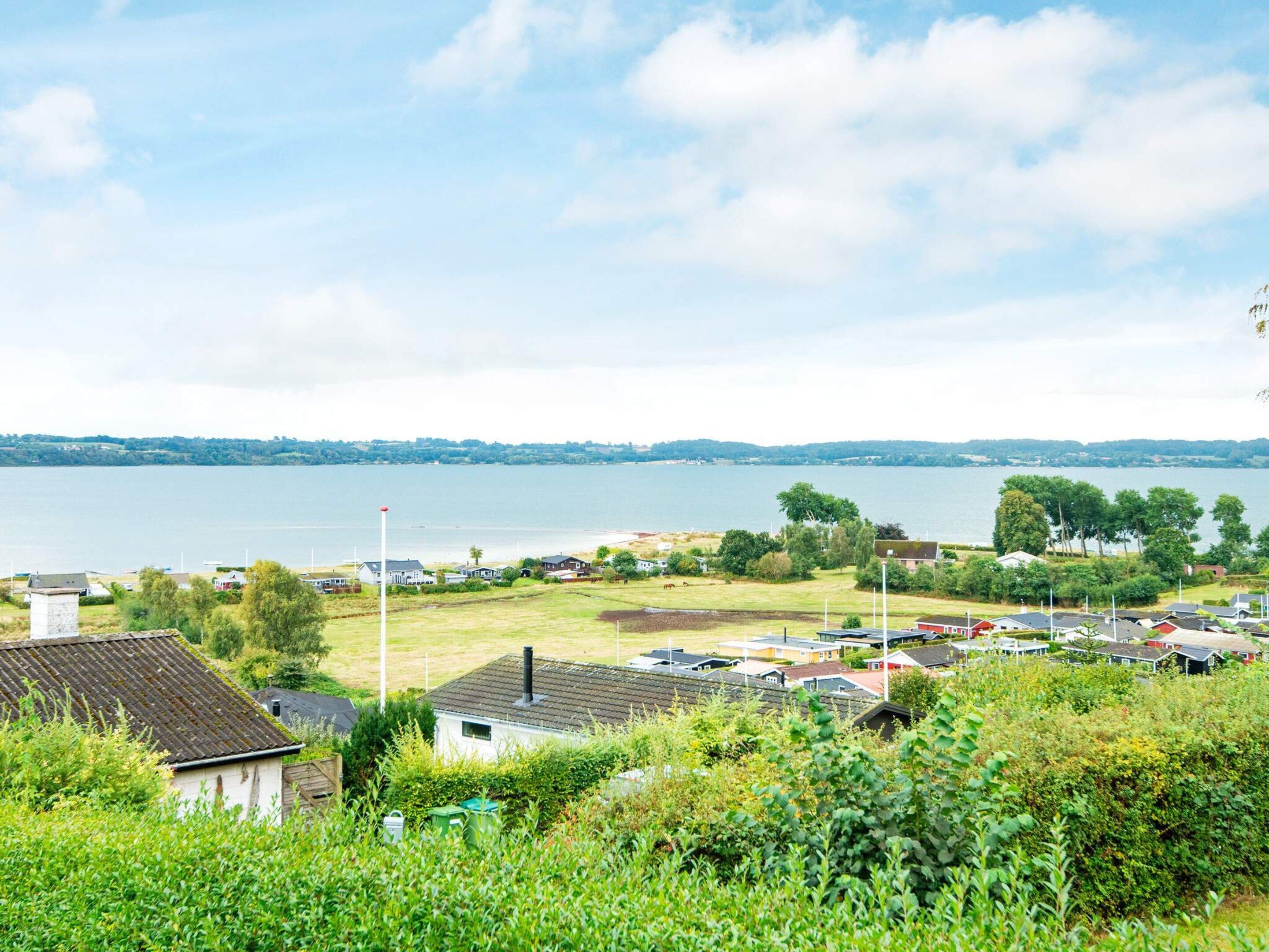 A residential area with houses, a grassy field, and a body of water in the background.