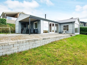 A modern house with a covered patio, a brick wall, and a grassy lawn. - 4 Person Holiday Home in Aabenraa (Aabenraa)