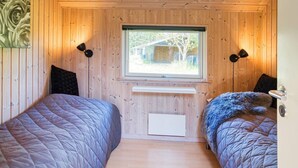 A cabin room with two beds, wooden walls, a window, and a small white shelf. - Luxury Retreat by Kramnitze - By Traum Ferienwohnungen (Rodby)
