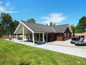 Une maison à deux étages avec un patio couvert, une cour arrière clôturée et une pelouse.