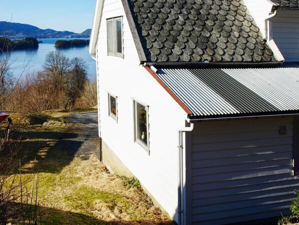 A white house with a metal roof, a garage, and a view of a lake and mountains.