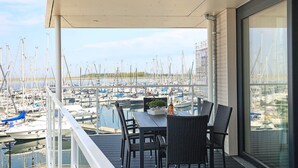 Un balcon avec une table et des chaises donnant sur une marina où sont amarrés de nombreux bateaux.