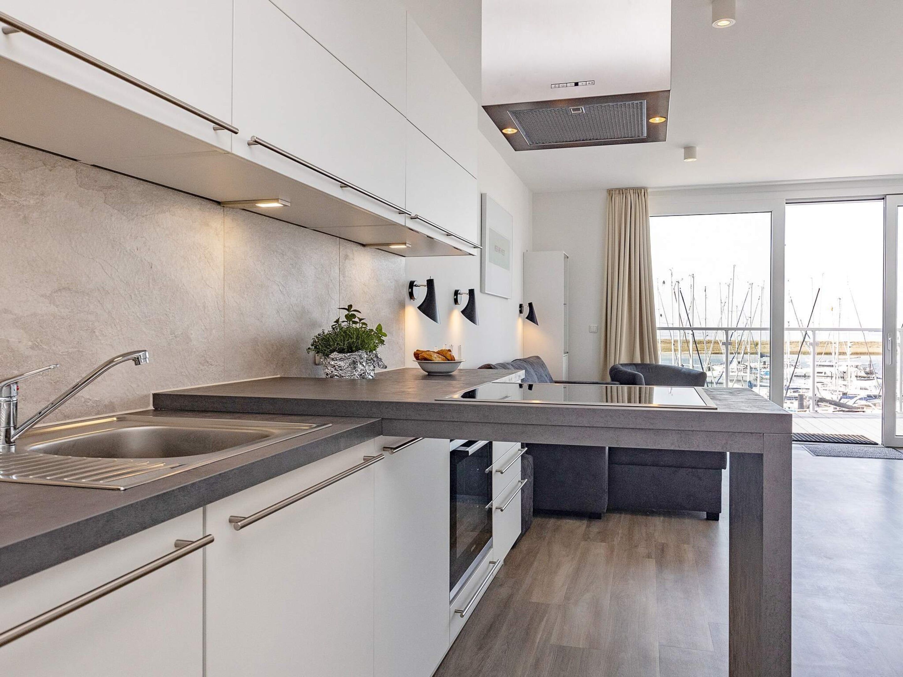 A modern kitchen with a central island, stainless steel appliances, and a view of a marina through large windows.