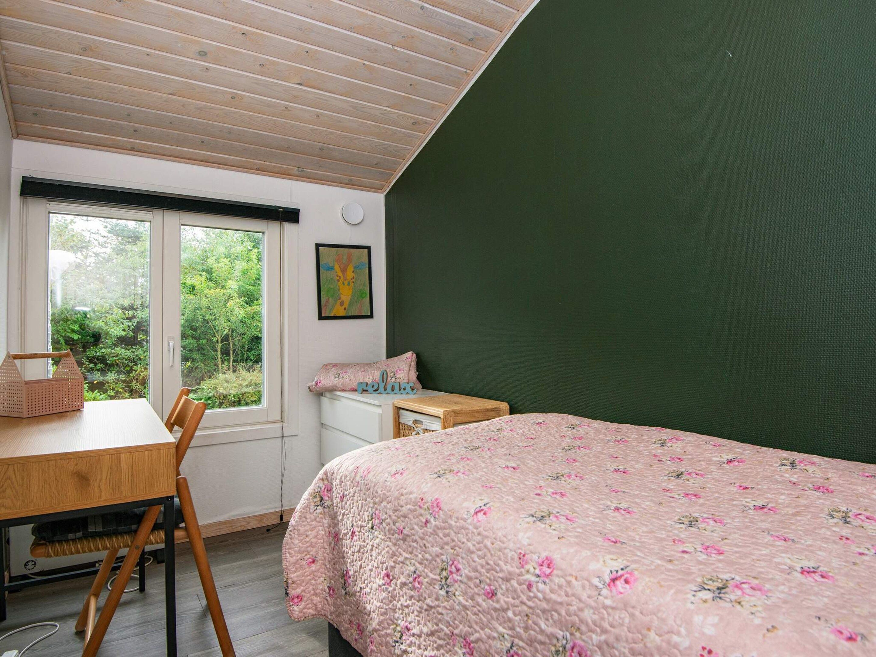 Un dormitorio con una cama, un escritorio y una ventana.