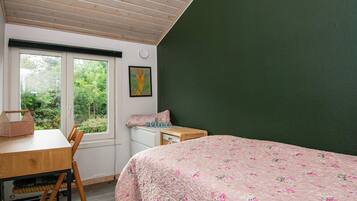 Un dormitorio con una cama, un escritorio y una ventana.
