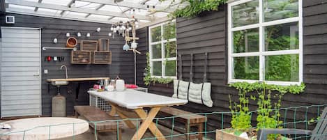 A covered patio with a table, chairs, and a bench.