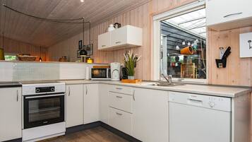 A modern kitchen with wooden paneling, a built-in oven, a microwave, and a Bosch dishwasher.