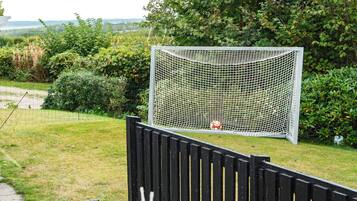 Una portería de fútbol en un jardín trasero con una valla de madera y follaje.