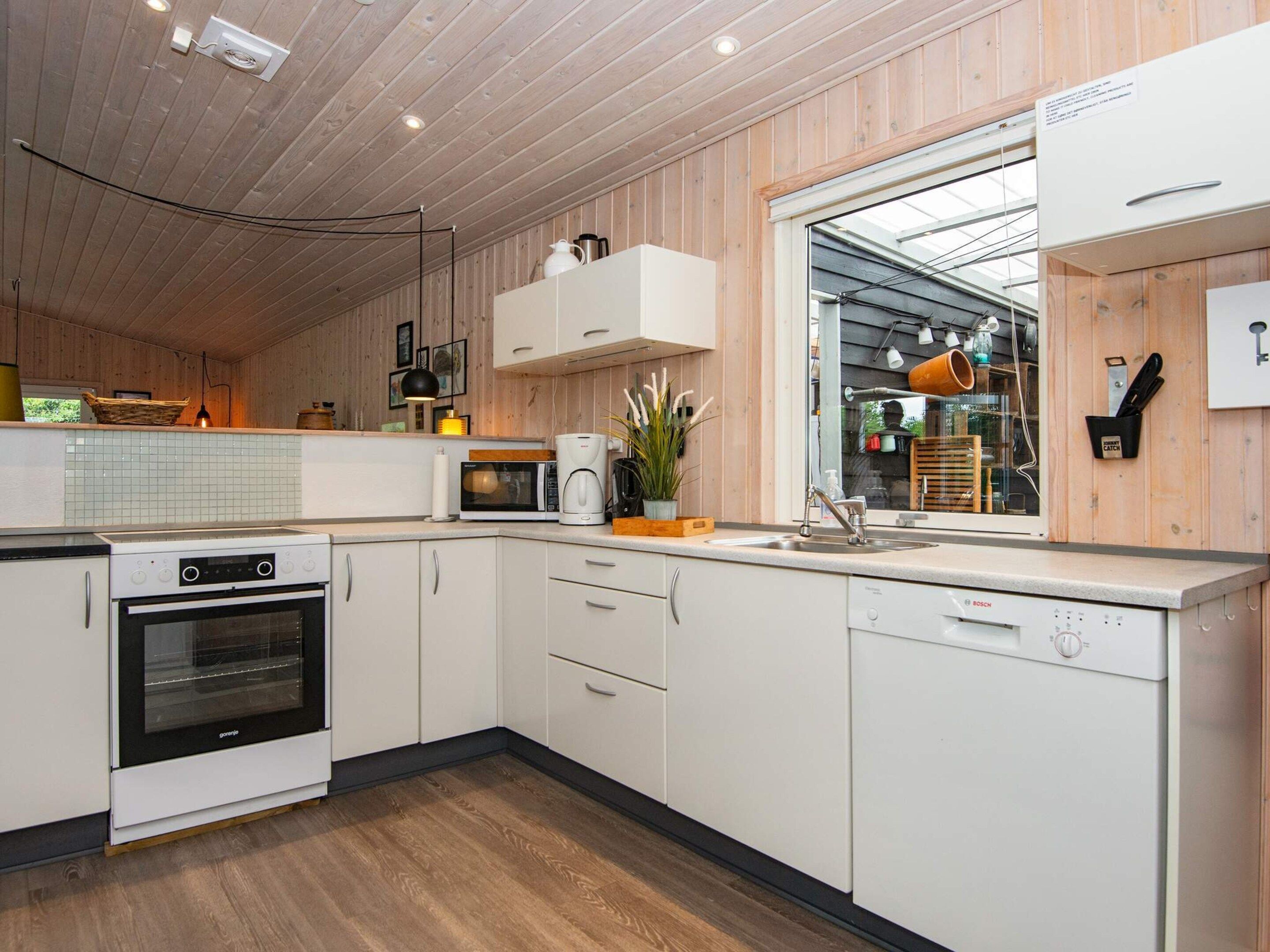 Een moderne keuken met witte kastjes, een Bosch vaatwasser, een magnetron en een ingebouwde oven.