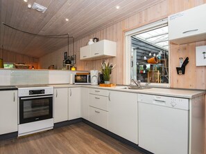 Een moderne keuken met witte kastjes, een Bosch vaatwasser, een magnetron en een ingebouwde oven.