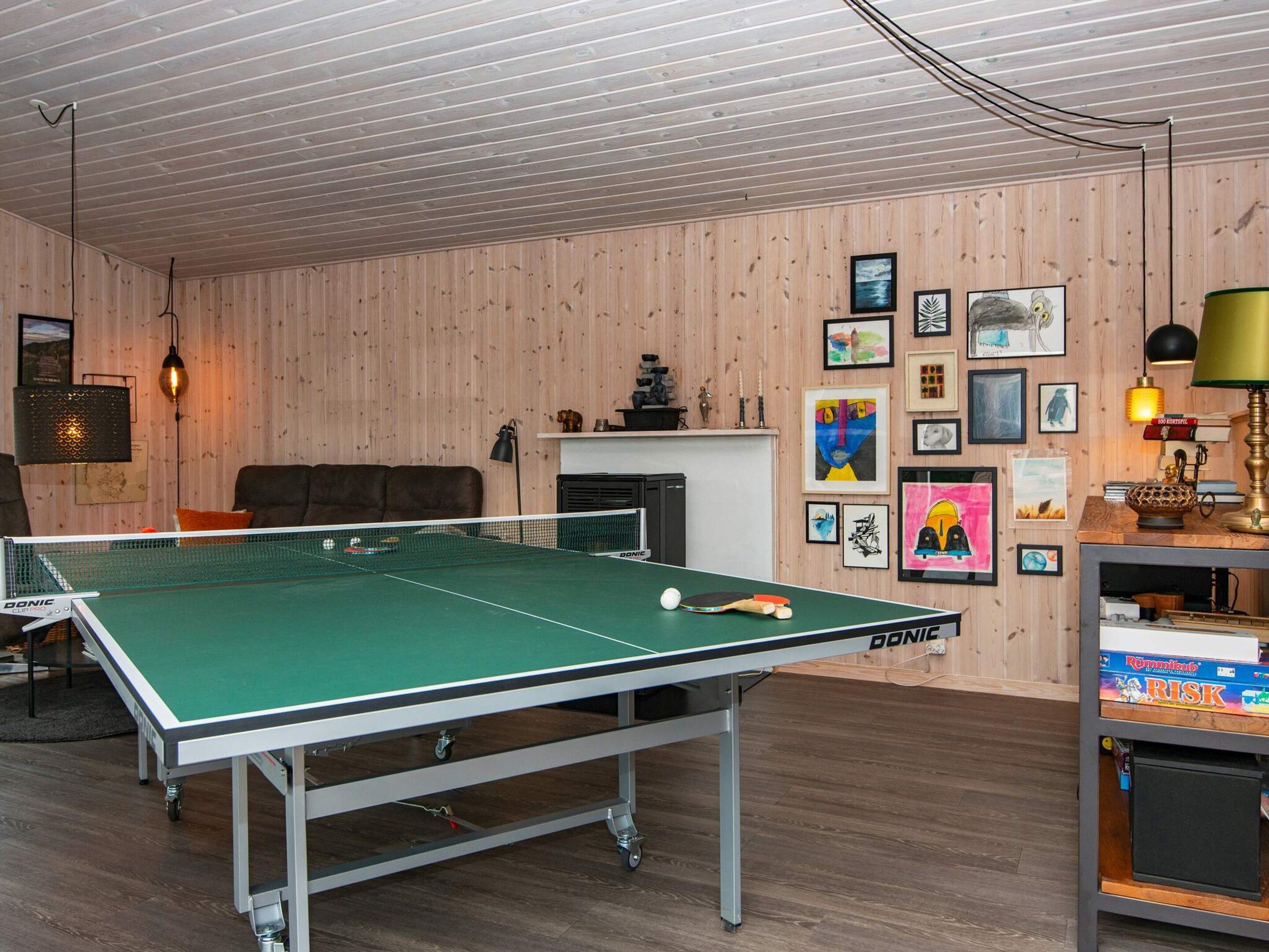 Taula de ping-pong en una habitació amb parets de fusta i una llar de foc.