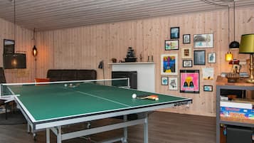 Taula de ping-pong en una habitació amb parets de fusta i una llar de foc.