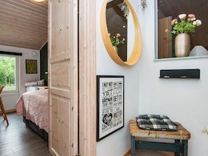 A bedroom with a bed, a mirror, a framed motivational quote, a small bench, and a window with a view of trees.