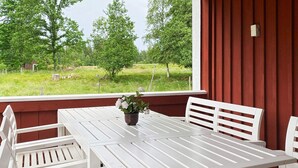 A white table and chairs set on a porch with a view of a green landscape. - 8 Person Holiday Home in Virestad (Virestad)