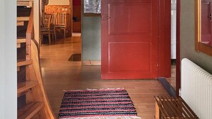 A wooden staircase leading to a room with a red door, a patterned rug, and a small table with chairs. - 8 Person Holiday Home in Virestad (Virestad)