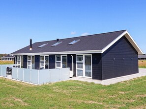 A modern beach house with a covered patio, large windows, and a sloped roof. - 10 Person Holiday Home in Lokken (Lokken)