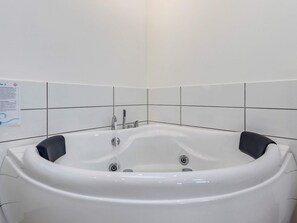 A white bathtub with two faucets and a control knob, set against a tiled wall with a sign. - 10 Person Holiday Home in Lokken (Lokken)