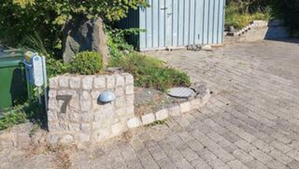 A paved driveway leading to a stone wall with a mailbox and a number plate. - 6 Person Holiday Home in Ebeltoft (Ebeltoft)