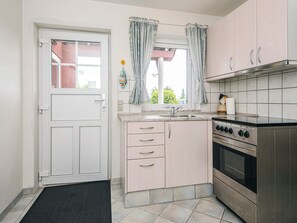 A compact kitchen with a stove, sink, and cabinets.