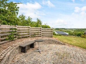Un espace extérieur aménagé avec un sol en briques, une clôture en bois et un banc.