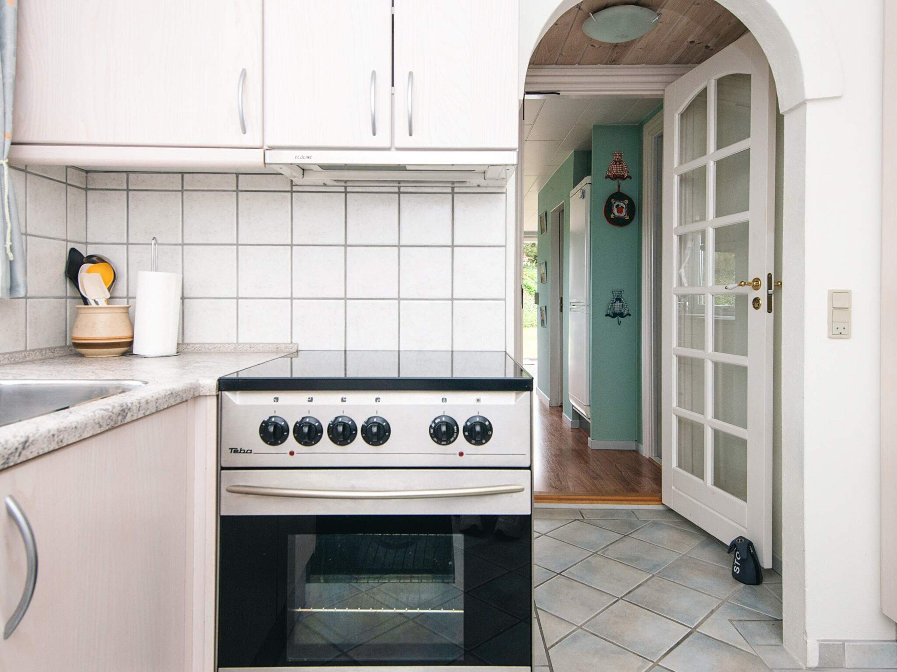 A kitchen with white cabinets, a stove, and a tiled backsplash.