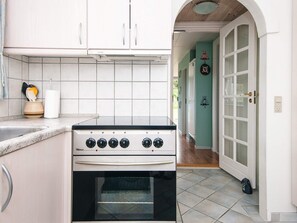 Una cocina con gabinetes blancos, estufa y salpicadero de azulejos.