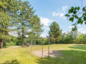 Un espace extérieur clos, doté d’une structure de jeux pour enfants et entouré d’arbres.
