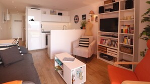 Ett modernt vardagsrum med en soffa, ett soffbord, en bokhylla och en tv.