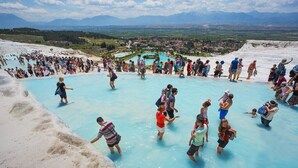 A geothermal hot spring with people bathing and walking around. - Pamukkale Apollon Garden (Denizli)
