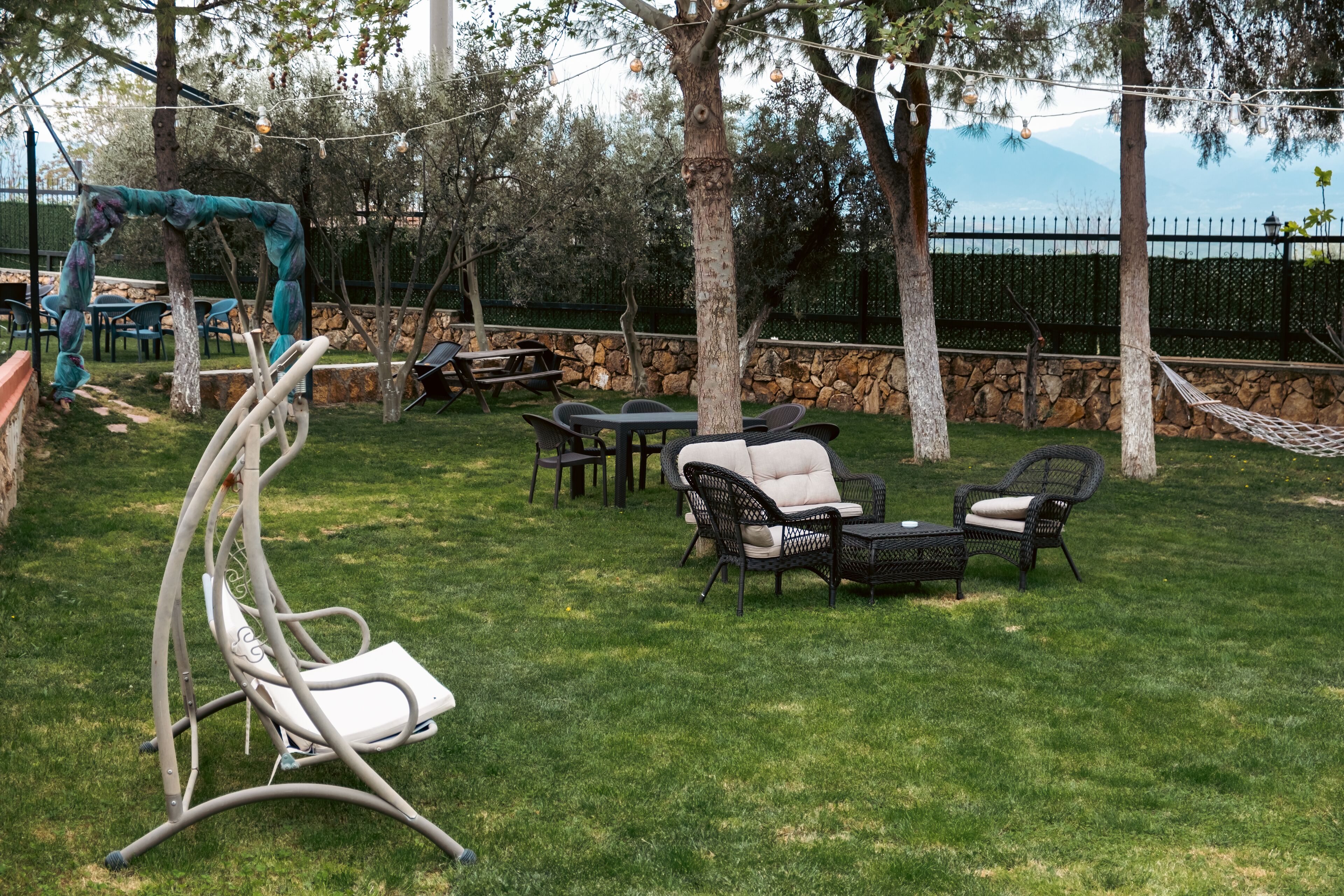 A backyard with a swing set, a dining table, and outdoor furniture.