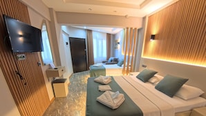 A modern hotel room with a large bed, a TV, a massage table, and a separate seating area. - Pamukkale Apollon Garden (Denizli)