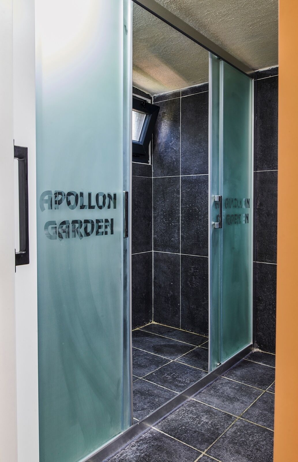 A hallway with frosted glass doors and black tiled walls.