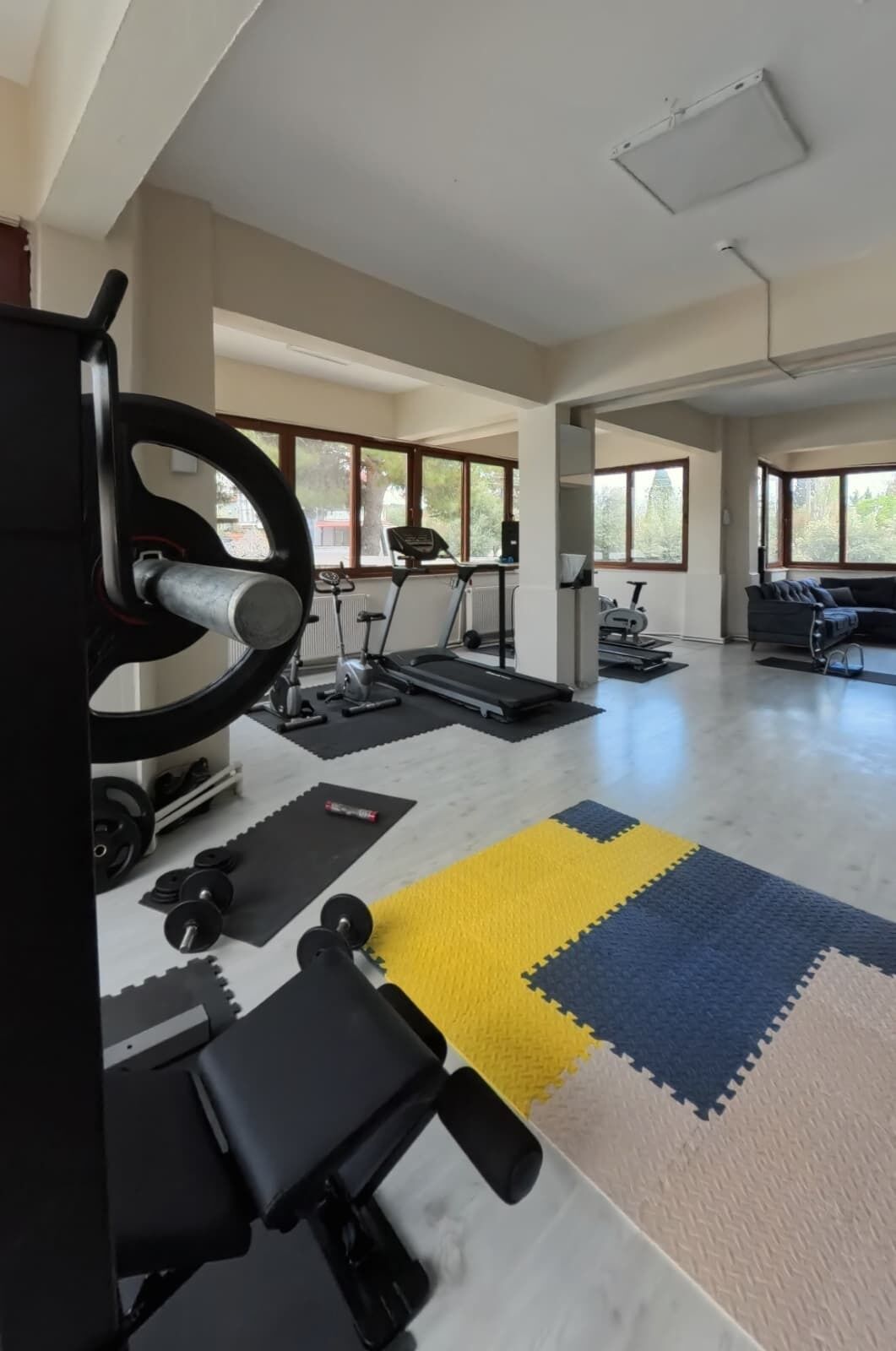 A spacious gym with treadmills, a weight bench, and a variety of weights.