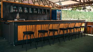 Una zona de bar con mostrador de madera, taburetes negros y un letrero de neón que dice 'Snack Bar'.