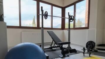 A gym with a blue exercise ball, a bench, and weightlifting equipment.
