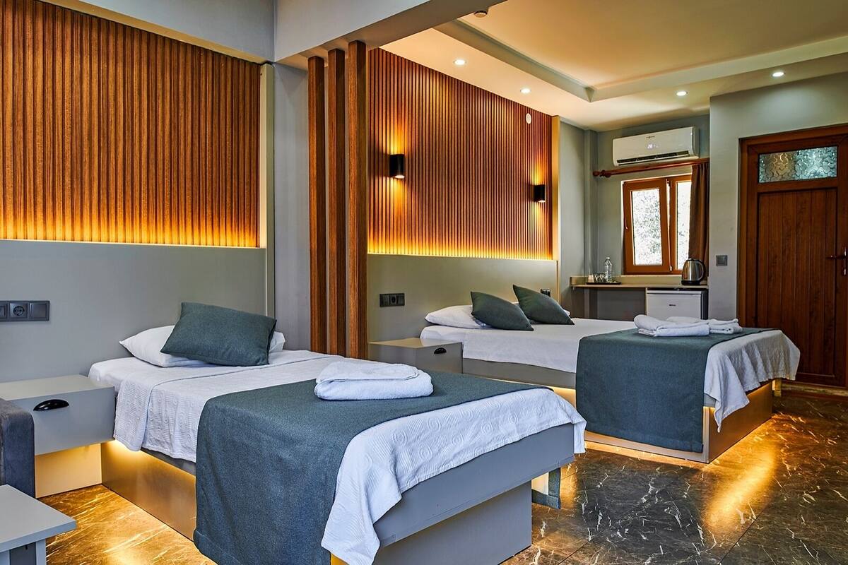 Una habitación de hotel moderna con dos camas, un escritorio pequeño y un espejo.