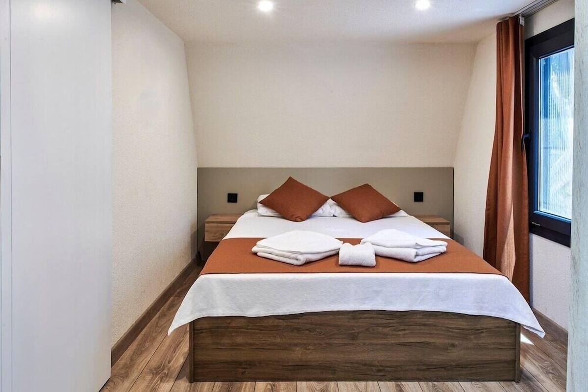Una cama individual con cabecera de madera, ropa de cama blanca y dos almohadas marrones.