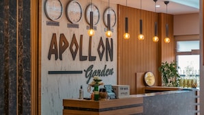 A reception desk with clocks displaying Istanbul, London, New York, and Tokyo times, a sign reading "APOLLON Garden," and a "TIP BOX" sign. - Pamukkale Apollon Garden (Denizli)