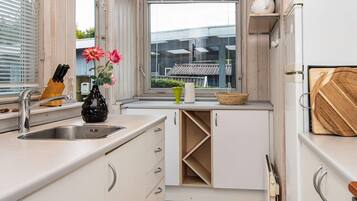 Una cocina moderna con un lavamanos, una ventana y vistas a edificios cercanos.