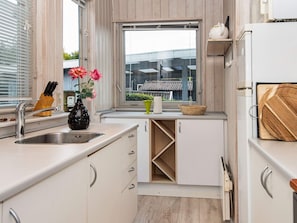 A modern kitchen with a sink, a window, and a view of buildings outside. - 4 Person Holiday Home in Ronde (Ronde)