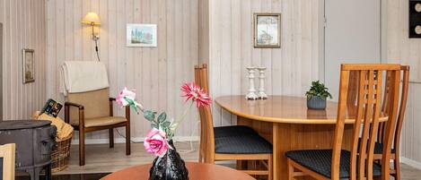 Un coin repas comprenant une table en bois, deux chaises, un vase avec des fleurs et des éléments de décoration fixés au mur.