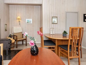 A dining area with a wooden table, two chairs, a vase with flowers, and wall-mounted decor. - 4 Person Holiday Home in Ronde (Ronde)