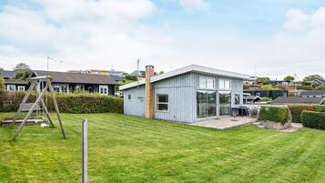A modern house with a large glass window, a brick chimney, and a grassy yard.