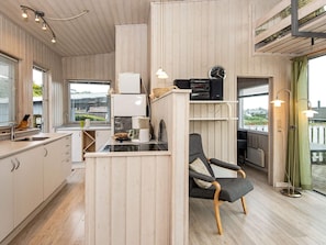 Ett kompakt kök med en matplats, träpanel på väggarna, en kaffemaskin och en klocka på väggen.