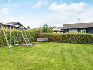 A residential backyard with a wooden swing set, a bench, and a well-maintained lawn. - 4 Person Holiday Home in Ronde (Ronde)