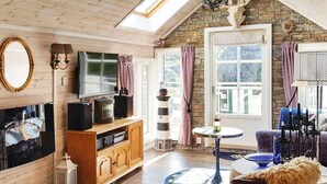A cozy living room with wooden floors, a stone wall, a large window, and a television. - 4 Star Holiday Home in Skudeneshavn (Karmoy)