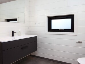 A modern bathroom with a white vanity, black faucet, and a window with a black frame. - 10 Person Holiday Home in Glesborg (Glesborg)