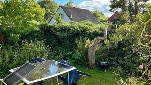 A garden with a table and chairs, a tree, and a house in the background. - 2 Person Holiday Home in Garsnas (Gärsnäs)