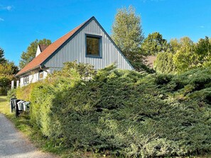 A single-story building with a sloped roof, surrounded by dense shrubbery. - 2 Person Holiday Home in Garsnas (Gärsnäs)